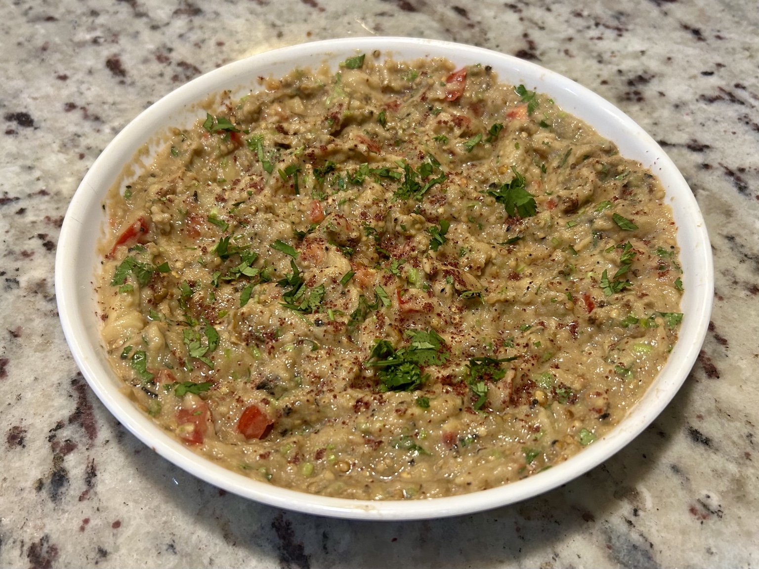 Finished textured baba ganoush with tomato, coriander, and sumac